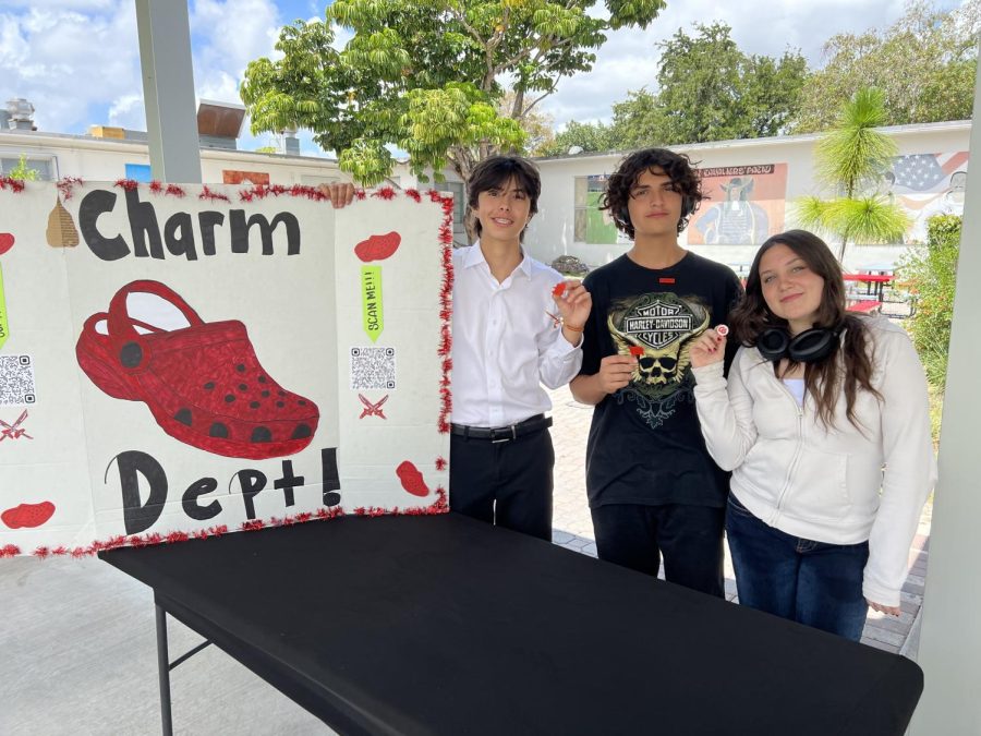 Head of Leadership Vinneccy (left), and volunteers Alysssa Toro and Romeo Puente (center) pose the four different charm designs created to sell.