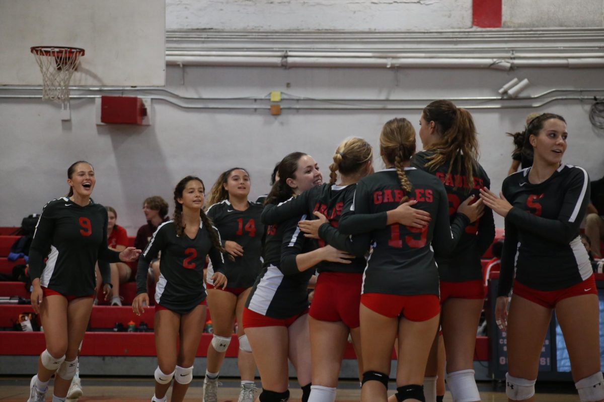 The varsity team storms the court after a three set victory over Mast Academy. Each member is all for teamwork and hugs. 