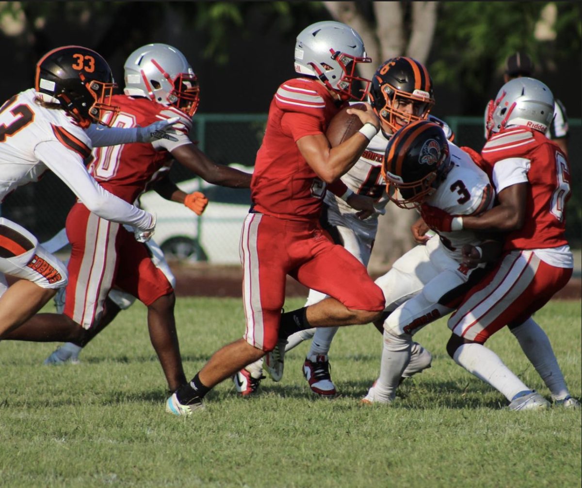 Entering into their second game of the season, senior starting quarterback, Andreus Rios runs with the ball along with his fellow teammates defending.