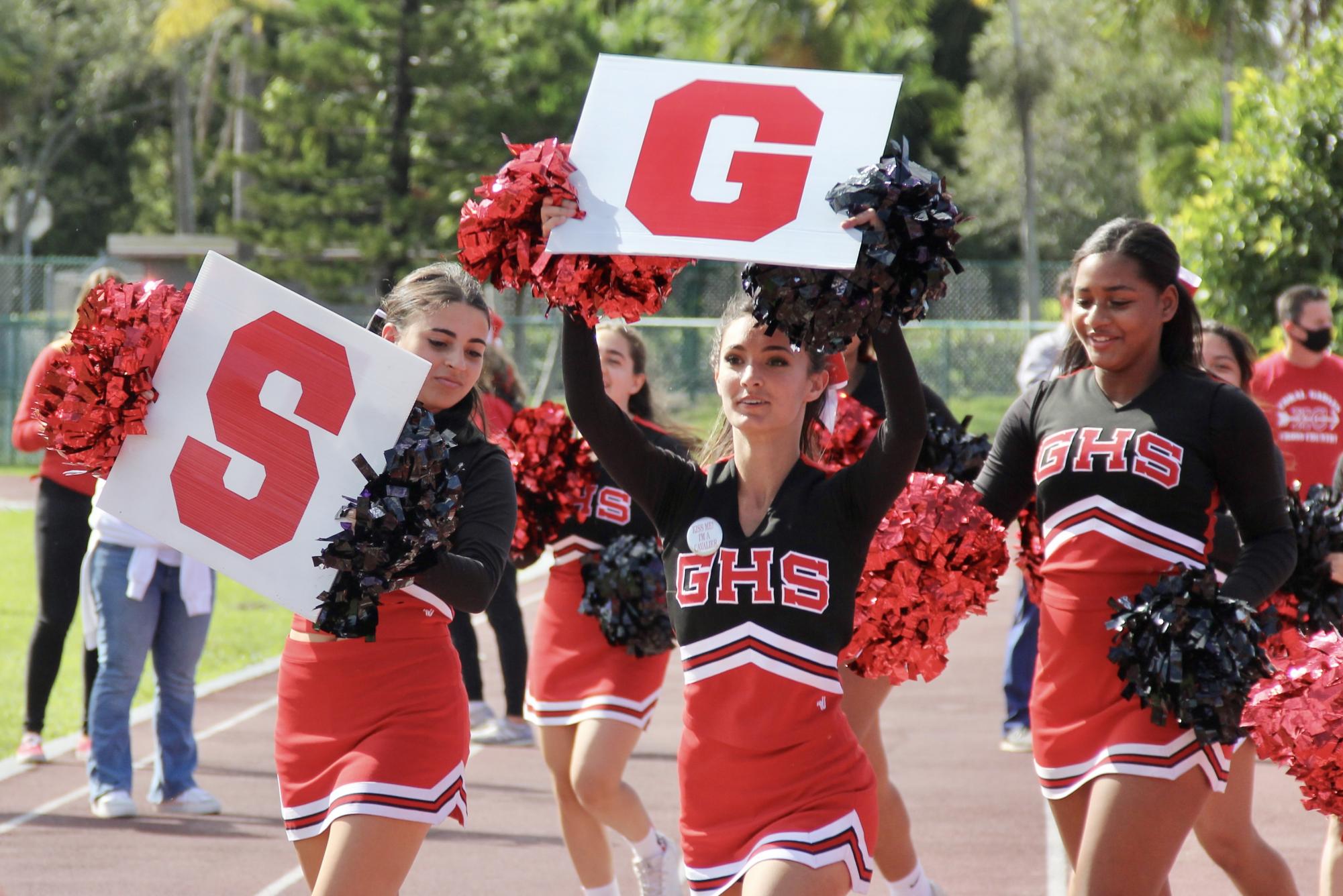 Cheer captains lead their team to cheer on the football team, with Gables signs.