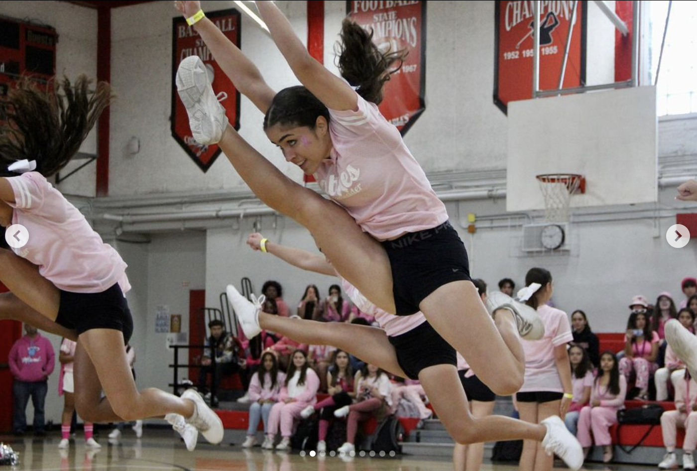 The Gablettes fly into the air as they execute their Pink pep rally perfomance.