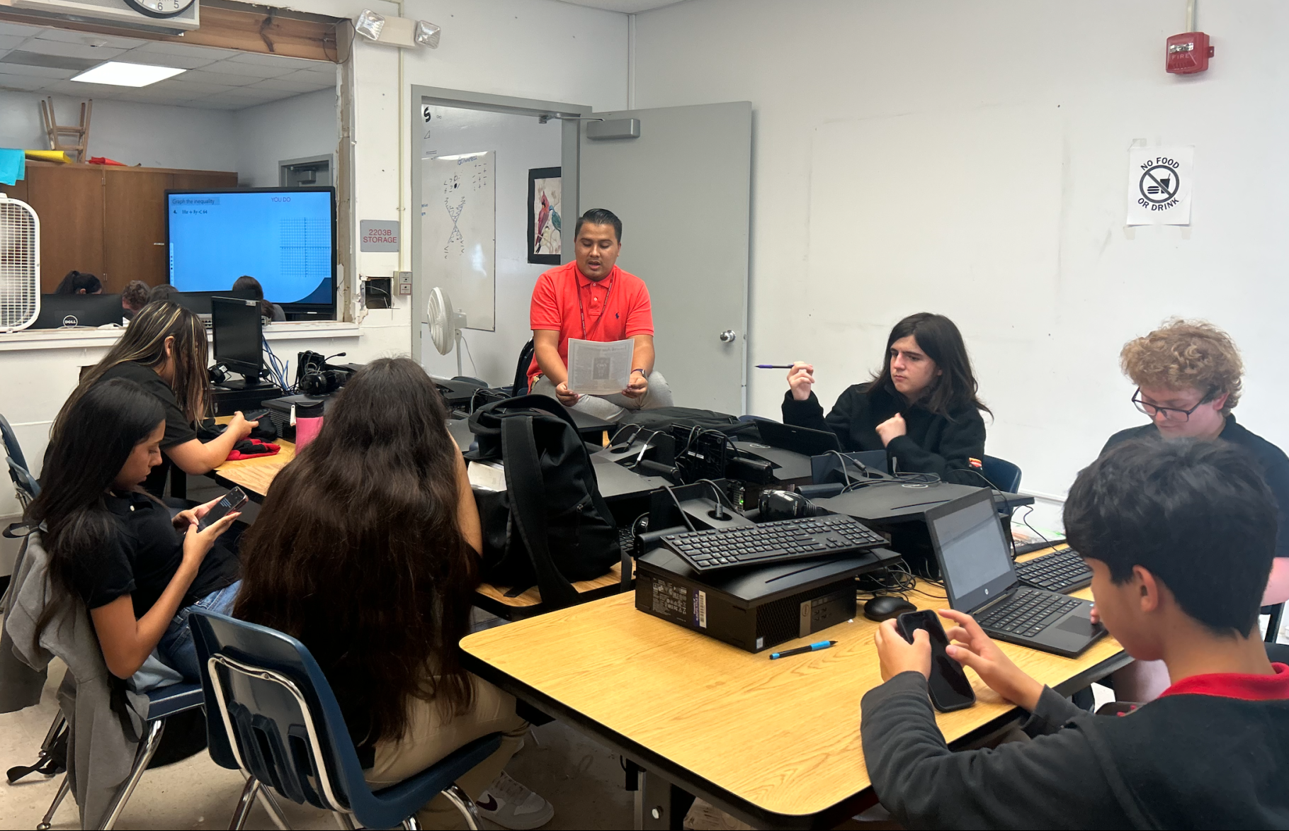Mr. Diaz translates an English passage into Spanish for the ESOL students, as they write new vocabulary words shared on their cellphones. 
