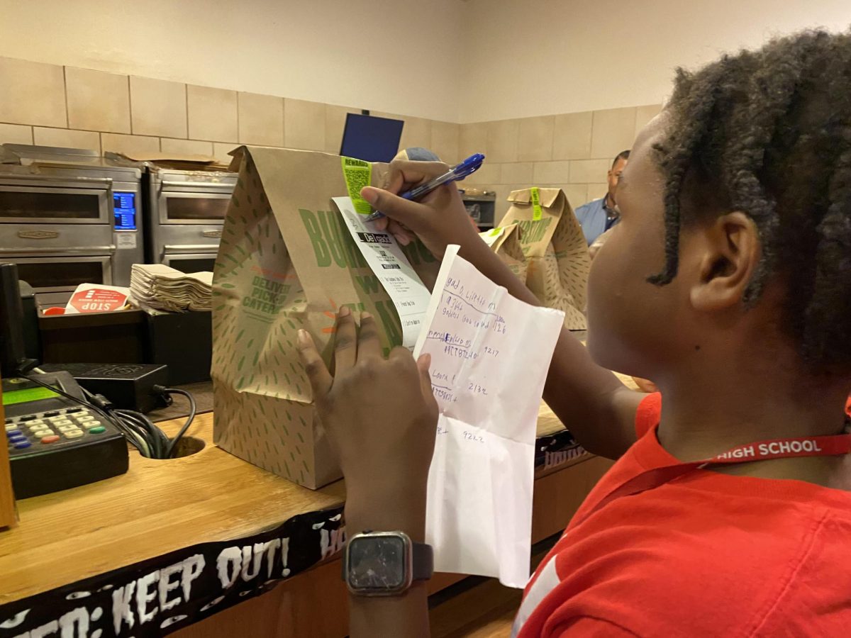 Freshman Jamal Coats writes the room number of a teacher's order. CavDash delivers to teachers all over campus.