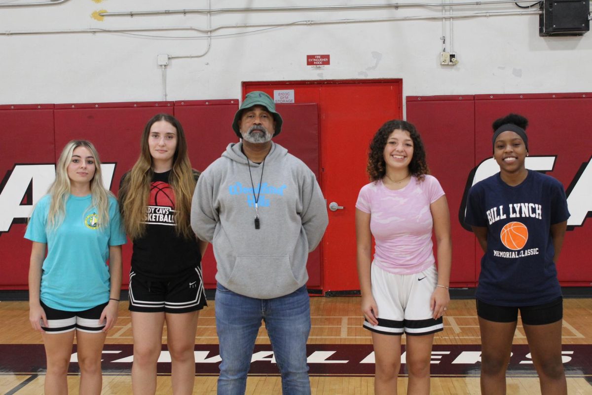 Coach Purcell stands besides his senior girls basketball captains feeling prideful and victorious.