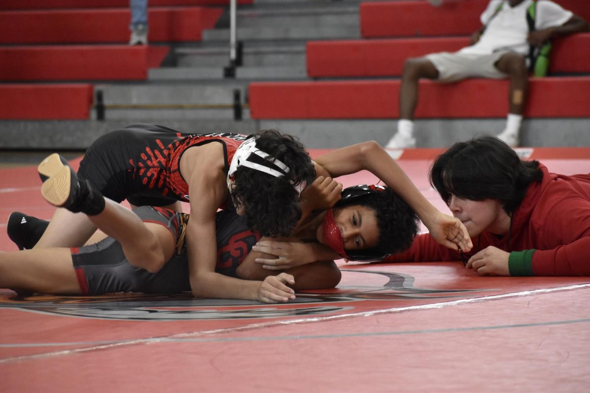 A wrestler is giving all his energy to keep his control over the fight as another wrestler attempts to topple him. 