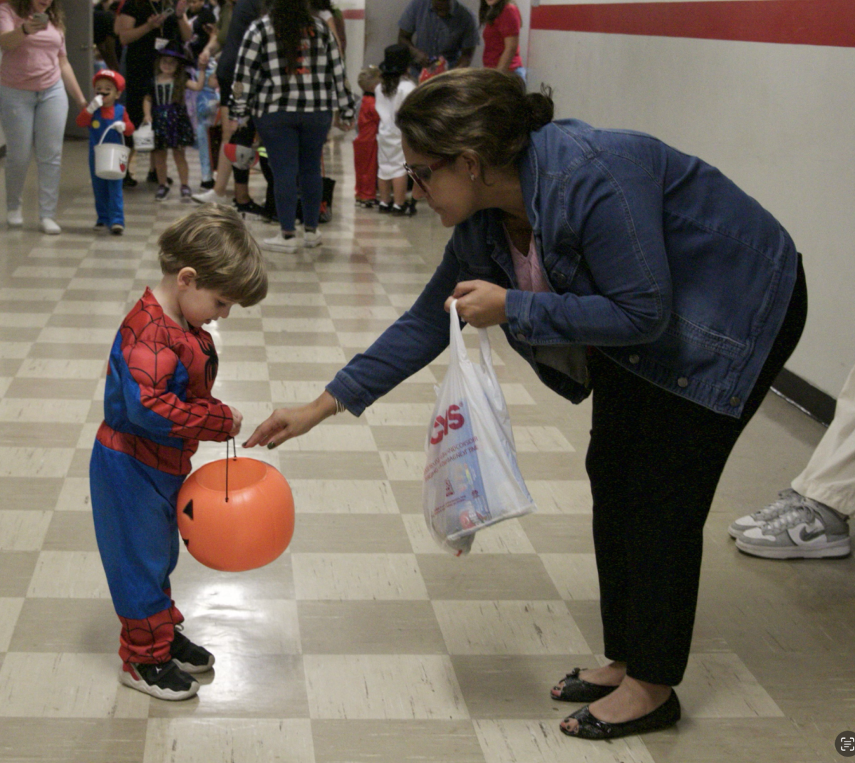 Handing down candy to a Little Cavalier dressed up as Spider-Man, Ms. Vazquezbello volunteered in making the children smiles.