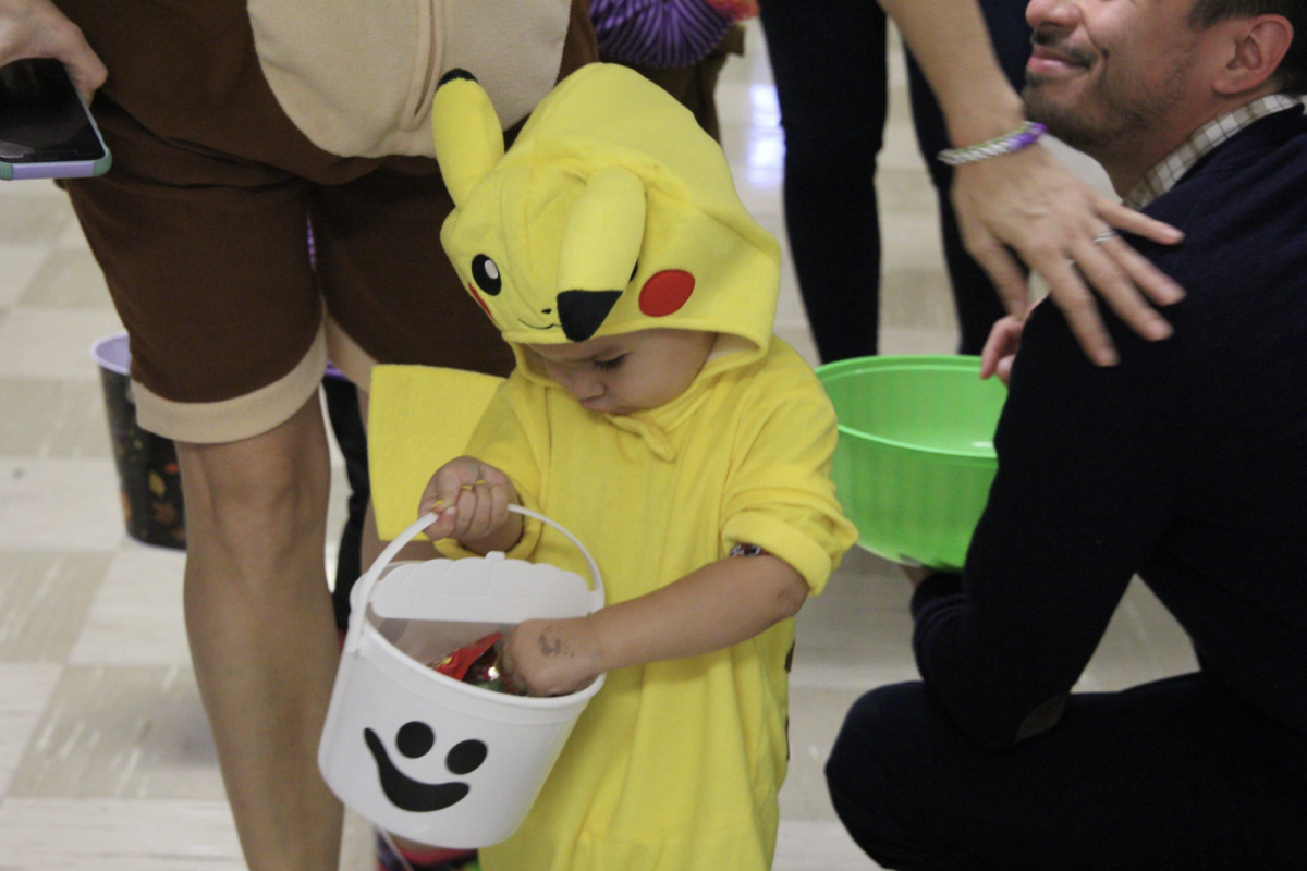A Little Cavalier dressed as Pikachu searches through his ghost basket, eager to find his favorite candy.