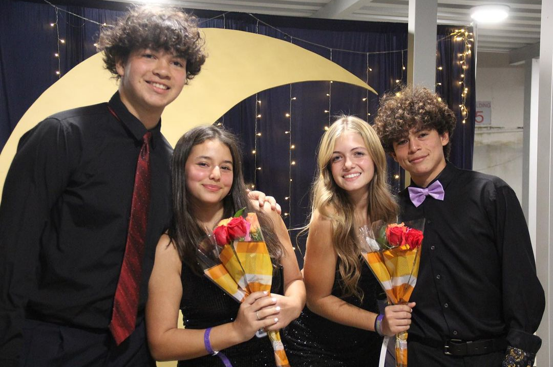 Cavaliers pose at the photo booth, where a large wooden crescent moon brings the Under the Stars theme to life. 