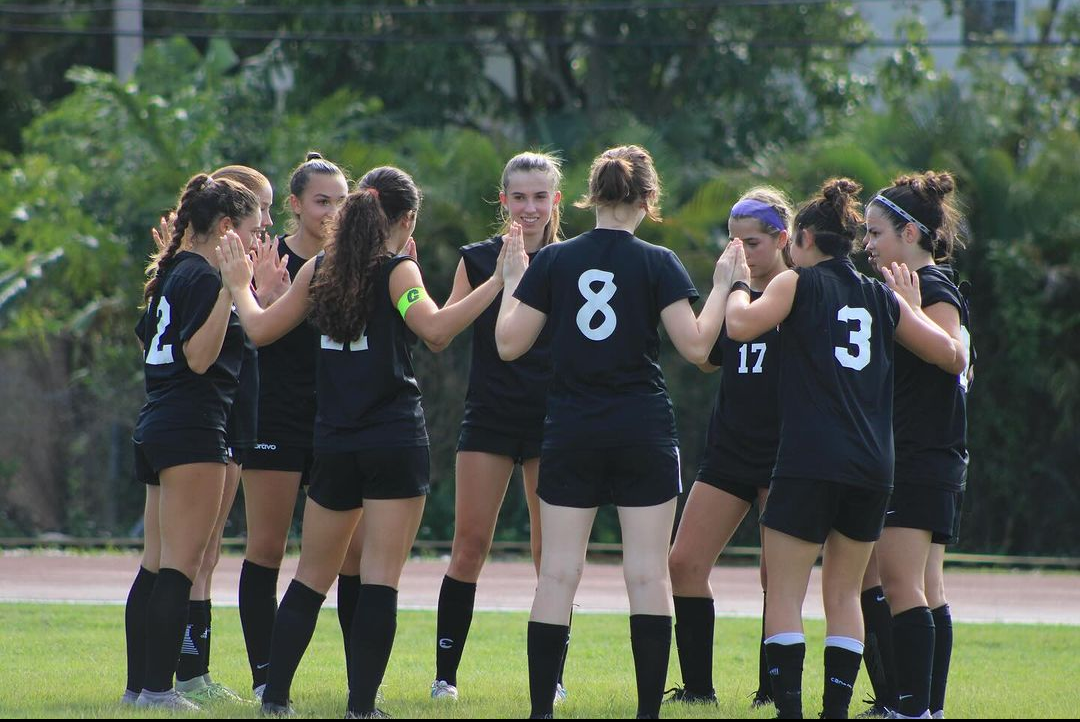 Forming a circle, the Cavalier soccer players stand together in their cleats. The captain encourage positive vibes and good game play during a pep talk. 