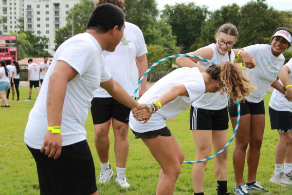 Seniors participate in the hula-hoop game, passing the hula-hoop about their interlocked arms. 