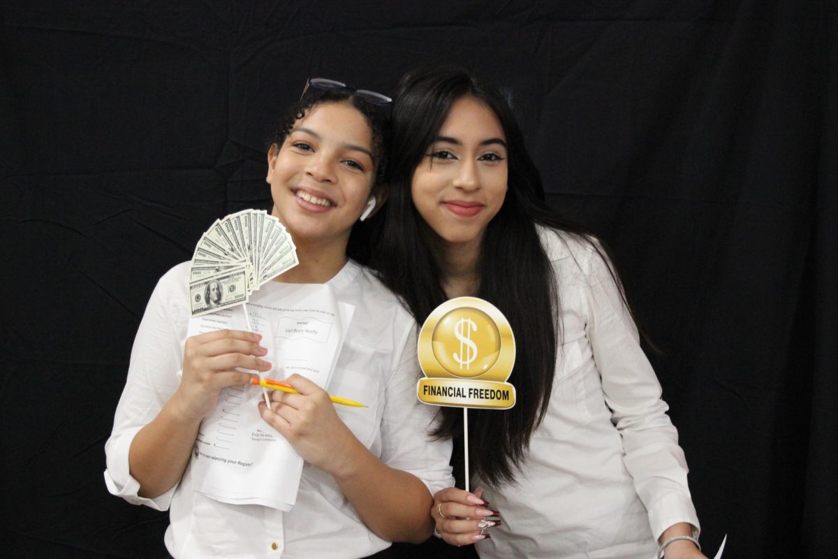 Showcasing budgeting skills at Ed-Fed's reality fair known as Mad City Money, a pair of AOF students pose with money-related props capturing the insightfulness of the event.