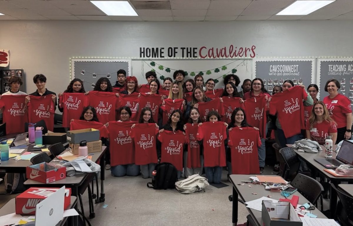 The Teaching Academy gathers around eagerly showing off the shirts personally delivered to them from Miami-Dade College.