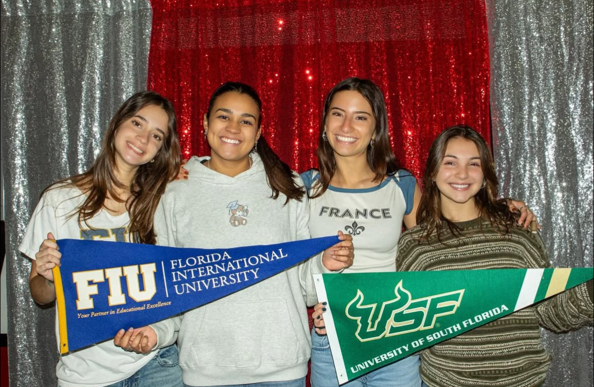 Seniors Emma Rivera, Cinthia Cruz, Chiara Ortiz and Melissa Hernandez smile with flags from Florida international University and University of South Florida.