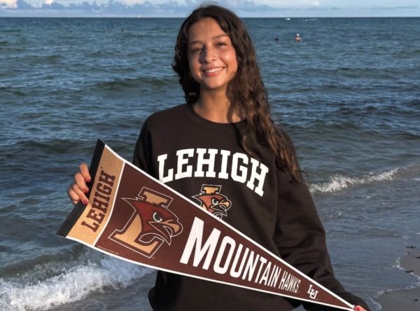 Proudly representing the college she is committed to play Division 1 Volleyball for, junior Natasha Macau poses for a photo with her Lehigh University sweatshirt and "Mountain Hawks" banner on the beach.